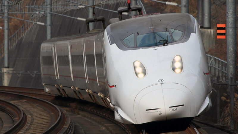 日本各地へ伸びる新幹線網。九州新幹線は全線開業15周年














画像提供：JR九州
1964年10月1日、1964東京オリンピックの開催を目前に、“夢の超特急”と呼ばれた東海道新幹線が東京～新大阪で開業した。その後、新大阪～岡山に開業した山陽新幹線は1975年3月10日、博多駅へ乗り入れて全線開業した。
一方、1982年6月23日に大宮～盛岡で先行開業した東北新幹線は、以降段階的に延伸し、2010年12月4日に新青森まで全線開業した。
1982年11月15日、上越新幹線が大宮～新潟において開業した。
長野オリンピックの開催を控えた1997年10月1日、高崎～長野において北陸新幹線が開業した。2015年3月14日に長野～金沢が開業した北陸新幹線は、2024年3月16日、金沢～敦賀へ延伸している。
2004年3月13日に新八代～鹿児島中央で部分開業した九州新幹線は、2011年3月12日に博多～新八代が開業し、2026年に全線開業15周年を迎える。
2016年3月26日には、新青森～新函館北斗で北海道新幹線が開業した。2022年9月23日、武雄温泉～長崎において西九州新幹線が営業運転を開始している。


























JR九州による九州新幹線全線開業15周年の記念プロジェクト













画像提供：JR九州
2026年3月12日に九州新幹線の全線開業15周年を迎えるJR九州では、各種の周年記念プロジェクトを展開している。
主な九州新幹線全線開業15周年記念プロジェクトを取り上げてみよう。

◎ペットボトルキャップモザイクアートプロジェクト














JR九州では、記念事業としてペットボトルキャップを活用した巨大モザイクアートを制作した。2025年12月10日～2026年2月28日のペットボトルキャップ収集期間中、博多駅や鹿児島本線の有人駅に回収箱を設けた。集まったペットボトルキャップ約4.2万個でモザイクアートを作成し、JR博多駅で6月末まで展示する。
作品の展示後、『認定NPO法人世界の子どもへワクチンを日本委員会』を通じて、約860個で1人分のポリオワクチンとなり、途上国のワクチン支援に活用される。

◎つばめの大冒険





















画像提供：JR九州
九州新幹線全線開業15周年を迎えるJR九州は、記念プロジェクト『つばめの大冒険』を始動する。2016年の熊本地震で被災した九州新幹線800系つばめU005編成の1号車を修繕・再塗装し、10年ぶりに“復活”させる。
熊本から海路で九州各地を巡り、15年の感謝を伝える“感謝の旅”を展開した後、博多駅前広場で約10日間公開する予定だ。



◎15周年記念で2種類の特別きっぷを発売
















画像提供：JR九州
JR九州は、全線開業15周年記念事業として、2種類の特別きっぷを発売する。
第1弾は、3月14・15日限定の『九州ドリームガチャ・フリーきっぷ』であり、購入アプリによる抽選でJR九州全線、または九州新幹線全線の1日乗り放題きっぷを手にすることができる。
第2弾としては、4月10～19日に利用できる『九州大冒険きっぷ』を発売する。

整備計画の決定から30余年で九州新幹線は部分開業














画像提供：JR九州
九州新幹線の始まりは約半世紀前、1973年11月に北海道、東北（盛岡～青森）、北陸とともに九州（鹿児島・長崎）の整備計画が決定したことによる。しかし、1982年9月、国鉄の財政悪化により、整備新幹線計画の当面見合わせが閣議決定された。
その後、国鉄分割民営化によって1987年4月、JR九州が発足した。
1991年9月、新八代～西鹿児島（現：鹿児島中央）において、スーパー特急方式で着工に至った。その後、2001年4月に全線フル規格へ変更した。
2004年3月13日、新八代～鹿児島中央（旧：西鹿児島）において、九州新幹線が部分開業した。新幹線開業前の鹿児島本線において、博多～八代は複線で最高時速130キロだった。一方、八代～西鹿児島は単線区間が多い上、最高時速も95キロに抑えられていた。そして、八代以南はカーブが多く、最高速度で運転可能な区間も限られていたため、所要時間が長かった。
このため、部分開業でも九州新幹線のインパクトは大きかった。新八代（八代）～鹿児島中央の所要時間は、従来の2時間以上から35分に短縮された。博多～鹿児島中央は、新八代で同一ホーム乗り換えのリレーつばめ方式により、従来の約4時間から最速2時間10分となり、時間短縮効果は特に大きかった。

全線開業以来、幾多の苦難を乗り越えて来た九州新幹線














画像提供：JR九州
九州新幹線が博多駅に乗り入れて全線開業した2011年3月12日は、東日本大震災発生の翌日だった。このため、JR博多駅で予定されていた記念式典やテープカット、祝賀イベント、さらに各駅での祝賀行事も自粛された。また、九州新幹線全線開業のテレビCMもオンエア自粛となり、静かなスタートとなった。
九州新幹線の全線開業5周年となる2016年には、4月14日・16日に熊本地震が発生した。前震発生時の4月14日21時26分頃、熊本駅の南側1キロ付近において、車両基地へ向かって時速80キロで回送中だった800系新幹線（U005編成・6両編成）の全車が脱線した。13日後の4月27日には、全線復旧を遂げている。
九州新幹線の全線開業10周年となる2021年3月12日は、新型コロナウイルス感染症による深刻なパンデミック状況下だった。該当年度である2020年度においては、経済活動が停滞し、九州新幹線の平均通過人員・旅客運輸収入はともに過去最低を記録した。
コロナ禍後、九州新幹線の平均通過人員・旅客運輸収入は、順調な回復を見せている。2022年9月23日には、武雄温泉～長崎において西九州新幹線が開業し、九州内では新幹線2路線体制となった。

九州新幹線はJR九州の鉄道旅客収入の1/3強を稼ぎ出す
JR九州は毎年、『交通・営業データ：線区別ご利用状況』を公開している。最新データとなる2024年度の平均通過人員・旅客運輸収入によると、新幹線2路線と在来線21路線を合計した営業距離は2,320.8キロだった。このうち358.5キロは新幹線（九州新幹線288.9キロ：西九州新幹線69.6キロ）、在来線は1,962.3キロである。JR九州の新幹線2路線が鉄道全体の営業距離に占める割合は、15.4％だ。
また、鉄道全体の平均通過人員は1日あたり16万4,543人だった。このうち2万3,793人は新幹線の人員（九州新幹線1万7,335人：西九州新幹線6,458人）であり、在来線の人員は14万750人だ。同様に新幹線2路線が鉄道全体の平均通過人員に占める割合は、14.5％である。
そして、新幹線2路線・在来線21路線の旅客運輸収入は、1,512億4,800万円だった。このうち605億4,000万円は新幹線（九州新幹線552億6,700万円：西九州新幹線52億7,300万円）、在来線は907億800万円となっている。鉄道の旅客運輸収入において、新幹線2路線が占める割合は、40.0％と大きい。
個別の路線を見た場合でも、九州新幹線（博多～鹿児島中央）の営業距離288.9キロは、日豊本線（小倉～鹿児島）の同462.6キロに次いで2番目に長い路線だ。
また、九州新幹線（同）の平均通過人員1万7,335人は、鹿児島本線（門司港～鹿児島）の同3万1,766人、篠栗線（吉塚～桂川）の同2万2,437人に次いで3番目に多い路線となっている。
さらに、九州新幹線（同）の旅客運輸収入552億6,700万円は、JR九州の全鉄道23路線において最多であり、全体に占める割合は36.5％だ。実にJR九州の鉄道旅客運輸収入の3分の1強を売り上げており、九州新幹線の存在感は大きい。
なお、九州新幹線は、独立行政法人鉄道建設・運輸施設整備支援機構が建設・保有しており、営業主体のJR九州は毎年120億円の貸付料を支払っている。





















出所：JR九州『交通・営業データ：線区別ご利用状況：（１）2024年度 平均通過人員・旅客運輸収入











出所：JR九州『交通・営業データ：線区別ご利用状況：（１）2024年度 平均通過人員・旅客運輸収入
九州新幹線が福岡・九州の社会・経済に何をもたらしたのか
博多～鹿児島中央を最速1時間16分、新大阪～鹿児島中央を同3時間41分で結ぶ九州新幹線は、福岡市をはじめ九州の地域社会や地元経済にどのような影響をもたらしてきたのだろうか。そして今後、どのような未来へ導いていくのか。
九州大学大学院経済学研究院の産業・企業システム部門に所属し、日本経済史を研究する鷲崎俊太郎准教授は、このテーマについて下記のように考える。
鷲崎俊太郎准教授
九州新幹線の全線開業で福岡～熊本～鹿児島という”九州の背骨”となる縦ラインを中心に「九州の新幹線化」ともいえる現象がみられたと考えます。
従来、自己完結していた九州内の各都市における経済活動は、九州新幹線の全線開業で福岡市との結びつきを強め、福岡市における経済活動も増えました。その半面、各都市の地元での経済活動は減少するという傾向が見られます。
つまり、九州新幹線の全線開業で福岡市の存在感が一層際立った結果、福岡市の九州における管理中枢機能は、さらに高まりました。このような現象は、特に東京本社や大阪本社などの企業における九州内の支店・営業所網の変化などからも読み取れます。
一方、九州新幹線の使命の一つは、福岡市に集まってくる人の九州全体への還流だと考えます。例えば、福岡市に集中しがちなインバウンド客を九州各地へ周遊させる上での”命綱”ともいえるのが九州新幹線です。特に世界遺産ツーリズムが魅力的な海外観光客に対しては、九州内の明治日本の産業革命遺産や潜伏キリシタン関連遺産を大いに活用していくべきではないでしょうか。
全線開業以来、幾多の困難に直面してきた九州新幹線が自らの本領を発揮するのは、今後だと考えて期待しています。














九州大学大学院経済学研究院産業・企業システム部門の鷲崎俊太郎准教授

最近15年で都市としての成長を加速し続ける福岡市
九州新幹線が博多駅に乗り入れて全線開業した2011年以降、福岡市の成長は加速し続けている。
全線開業の翌2012年には、福岡都市高速道路が全線開通し、環状線となった。　
2014年に福岡市が国家戦略特区に指定され、翌2015年から天神ビッグバンが始動している。福岡市科学館が九大六本松キャンパス跡地に誕生したのは2017年のことであり、さらに翌2018年に福岡市総合体育館がアイランドシティに開館した。
博多コネクティッドがスタートした2019年には、G20福岡財務大臣・中央銀行総裁会議が開かれた。翌2020年は、国から『スタートアップ・エコシステム拠点都市』に指定された。2023年には、地下鉄七隈線（天神南～博多）が博多駅に乗り入れ、世界水泳選手権2023福岡大会も開催された。2025年、福岡空港第二滑走路が供用を開始。福岡市・天神地区ではワンビルをはじめ新たなビル群が相次いで誕生した。
九州新幹線が全線開業した2011年3月1日時点における福岡市の推計人口は146万8,069人、世帯数は70万9,698世帯だった。15年後の2026年2月1日現在の推計人口は2011年3月比で13.9％増の167万2,056人、世帯数は同27.6％増の90万5,799世帯となっている。
一方、『福岡市統計書』2024年版によると、2011年度の福岡市内総生産（名目）は、7兆365億9,200万円だった。一方、2022年度の市内総生産（同）は、8兆2,350億7,400万円となっており、この10年余りで17％増という伸びを示している。
　また、2011年度における福岡市の一般会計予算（当初）は7,661億円であり、市税収入は2,662億円だった。一方、福岡市が2026年2月16日に発表した2026年度一般会計当初予算案は、2011年度比47.7％増の1兆1,318億円で過去最大となる。市税収入も過去最高を更新する、同60.1％増の4,263億円となる見通しだ。
この15年間における福岡市の都市としての躍進は、注目に値する。







出所：福岡市総務企画局企画調整部統計調査課『令和４年度 福岡市民経済計算』


九州新幹線による九州のローカル交通網の維持を考える













JR九州は2026年2月10日、『2026年3月期第3四半期決算説明会』資料を発表した。同資料によると、JR九州グループの2026年3月期通期業績予想における営業収益は前期比7.6％増の4,891億円、営業利益は同23.9％増の731億円、経常利益は同21.4％増の723億円だった。
また、JR九州単体となる2026年3月期単体通期業績予想における営業収益は同12.7％増の2,715億円であり、うち鉄道旅客運輸収入は同13.5％増の1,717億円となっている。鉄道旅客運輸収入の内訳について、新幹線は同13.7％増の688億円、在来線は同13.4％増の1,029億円を予想する。鉄道旅客運輸収入の増加については、29年ぶりの運賃・料金改定が大きかった。
鉄道部門においては、旅客運輸収入の4割を占める新幹線の収益によって、九州各地のローカル線を支える構造となっている。地域の人々にとっての“足”であるローカル線の維持を図る上でも九州の大動脈である九州新幹線の果たす役割は大きいと考える。
◇　　◇　　◇　　◇
　九州新幹線の全線開業CMである『祝！九州』キャンペーンは、東日本大震災の発生によるオンエア自粛で“幻のCM”となった。その後2011年6月23日、世界3大広告賞の1つであるカンヌ国際広告祭において、祝！九州キャンペーンはアウトドア部門で金賞、メディア部門で銀賞に輝いた。
受賞作となったCMを締めくくるナレーションのメッセージは、未だ心に響き続けている。
「1つになった九州から新しい力が生まれています」
「1つになった九州から日本は楽しくなるはずです」
「九州新幹線、みなさんと一緒に全線開業です」

参照サイト
JR九州『交通・営業データ』
https://www.jrkyushu.co.jp/company/info/data/
JR九州『交通・営業データ：線区別ご利用状況：（１）2024年度 平均通過人員・旅客運輸収入』 
https://www.jrkyushu.co.jp/company/info/data/pdf/2024senku_250912.pdf
JR九州『～九州新幹線開業15周年記念～ペットボトルキャップ モザイクアートプロジェクト』 
https://www.jrkyushu.co.jp/byarea/fukuoka_saga/info/__icsFiles/afieldfile/2025/12/10/20251210_Kyushu_Shinkansen_15th_Anniversary_Plastic_Bottle_Cap_Art_Project.pdf
JR九州『九州新幹線全線開業15周年記念プロジェクト「つばめの大冒険」』 
https://www.jrkyushu.co.jp/common/inc/news/newtopics/__icsFiles/afieldfile/2026/01/22/20260122_Tsubames_Great_Adventure.pdf
JR九州『九州新幹線全線開業15周年を記念したおトクな割引きっぷの発売について』 
https://www.jrkyushu.co.jp/news/__icsFiles/afieldfile/2026/02/06/20260206_Kyushu_Shinkansen_15th_Anniversary_Discount_Tickets.pdf
大谷友男・富山国際大学現代社会学部准教授『九州新幹線（鹿児島ルート）の部分開業でのインパクト』 
https://www.pref.akita.lg.jp/uploads/public/archive_0000070203_00/%E3%80%90%E5%AF%8C%E5%B1%B1%E5%9B%BD%E9%9A%9B%E5%A4%A7%E5%AD%A6%E5%A4%A7%E8%B0%B7%E5%85%88%E7%94%9F%E3%80%91%E8%AC%9B%E6%BC%94%E8%B3%87%E6%96%99.pdf
国土交通省『九州新幹線（博多・新八代間）の貸付料の額について』 
https://www.mlit.go.jp/report/press/tetsudo03_hh_000026.html
国土交通省『九州新幹線（新八代・鹿児島中央間）の貸付料の額について』 
https://www.mlit.go.jp/kisha/kisha04/08/080312_.html
福岡市総務企画局企画調整部統計調査課『令和４年度 福岡市民経済計算』 
https://www.city.fukuoka.lg.jp/soki/tokeichosa/shisei/toukei/shiminkeizaikeisan/shiminkeizaikeisan.html
福岡市推計人口（毎月公表〔１日現在〕）
https://www.city.fukuoka.lg.jp/shisei/kouhou-hodo/hodo-happyo/2025/documents/20260201suikeijinko.pdf
福岡市『令和8年度当初予算案の概要』
https://www.city.fukuoka.lg.jp/zaisei/zaisei/shisei/documents/03_R8_gaiyou.pdf
JR九州『2026年3月期第3四半期決算説明会』（2026年2月10日）
https://www.jrkyushu.co.jp/company/ir/news/__icsFiles/afieldfile/2026/02/10/9142.FY2026.3q.material.ja.pdf
祝！九州 九州新幹線全線開CM180秒
https://www.bing.com/videos/riverview/relatedvideo?q=you+tube+jr+%e4%b9%9d%e5%b7%9e+%e6%96%b0%e5%b9%b9%e7%b7%9a&&mid=26DF8C0DCE9475F6F82126DF8C0DCE9475F6F821&churl=https%3a%2f%2fwww.youtube.com%2fchannel%2fUCzBu2qy047srA_pMP_Pl-Kw&FORM=VRDGAR

あわせて読みたい
新幹線が博多に来て50周年！博多～東京をつなぐ『ひかりライン』と福岡市のこれまで
https://fukuoka-leapup.jp/biz/202502.46654
